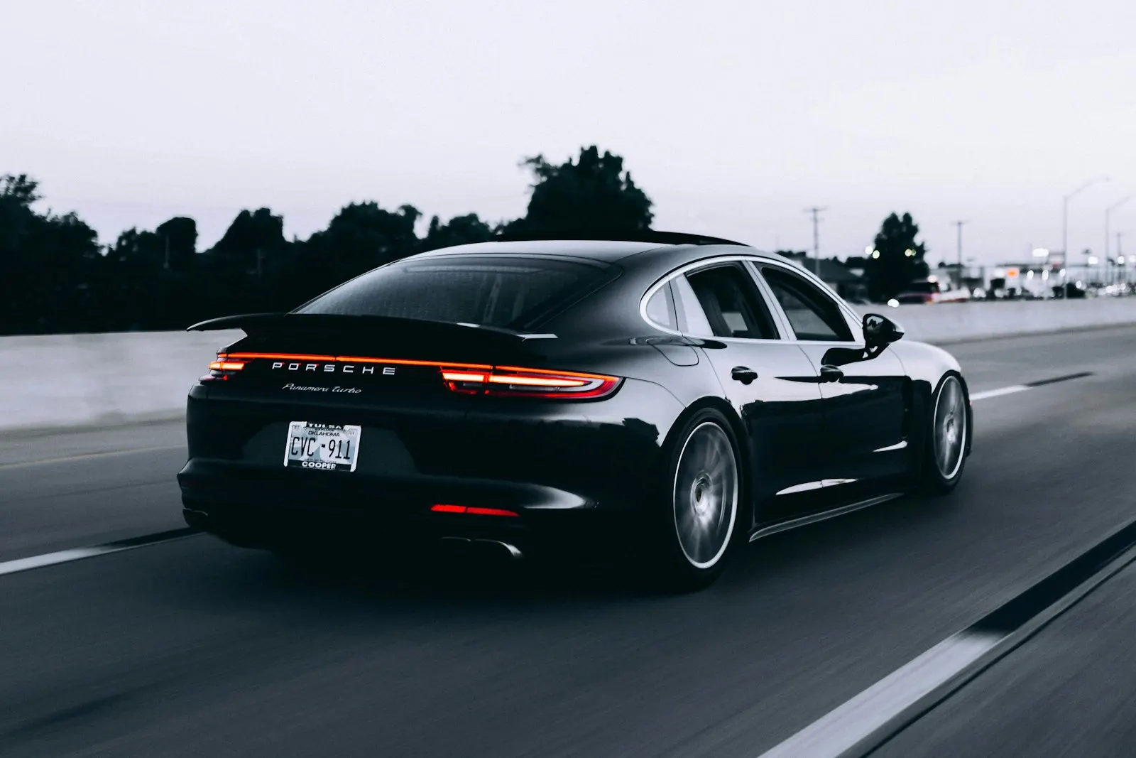 Black Porsche Panamera with a deep gloss finish driving at dusk